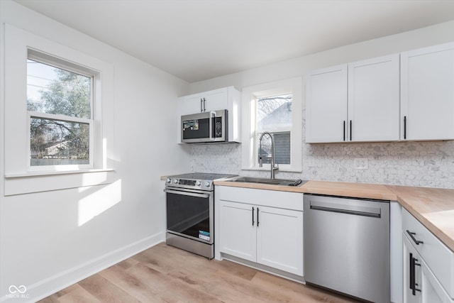 kitchen with white cabinetry, sink, light hardwood / wood-style flooring, backsplash, and appliances with stainless steel finishes