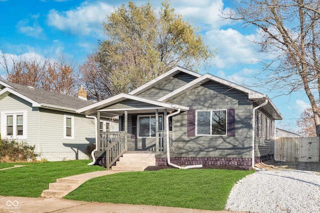 bungalow-style house featuring covered porch and a front yard