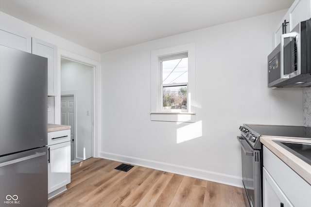 kitchen with white cabinets, light hardwood / wood-style floors, and stainless steel appliances