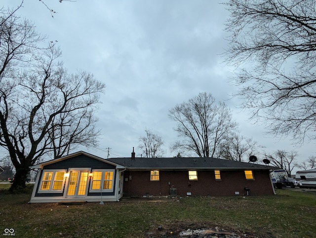 rear view of house featuring central air condition unit and a lawn