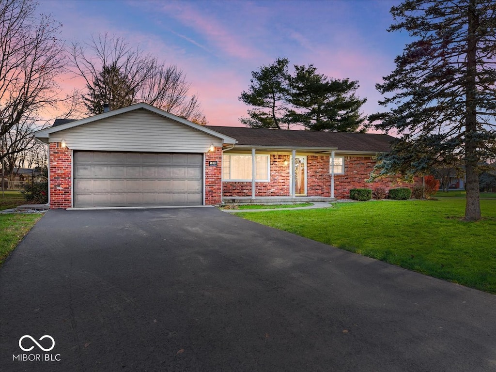 ranch-style house featuring a lawn and a garage