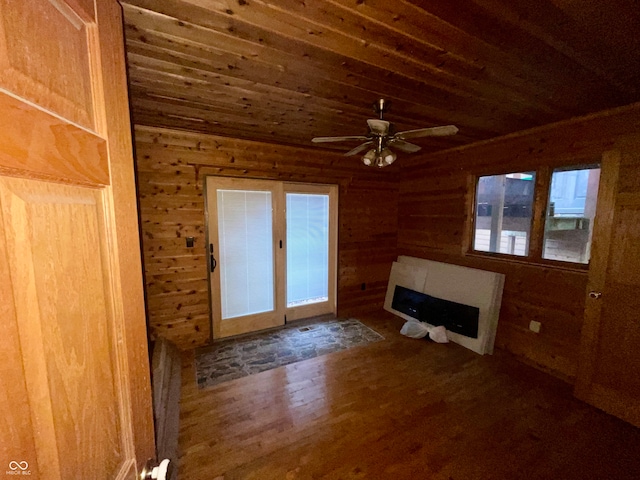 unfurnished living room with ceiling fan, dark hardwood / wood-style flooring, wooden ceiling, and wood walls