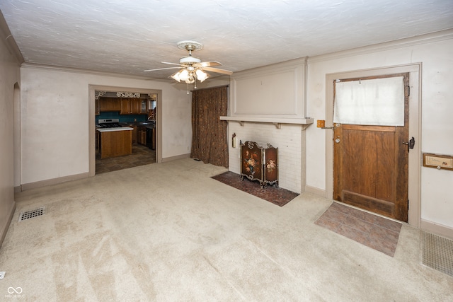 unfurnished living room with a textured ceiling, light colored carpet, ceiling fan, and ornamental molding