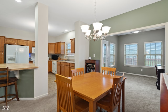 dining space with sink, light colored carpet, and a notable chandelier