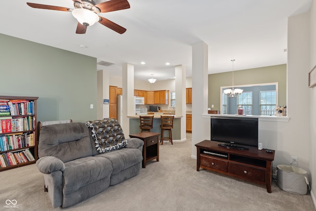 living room featuring light carpet and ceiling fan with notable chandelier