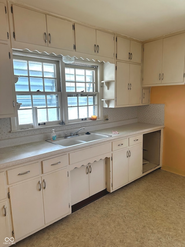 kitchen featuring white cabinets, sink, and tasteful backsplash