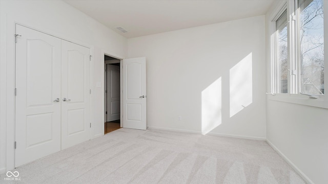 unfurnished bedroom with light colored carpet and a closet