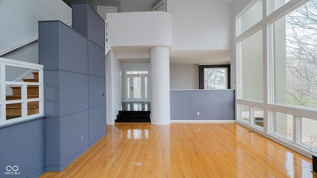 interior space with ornate columns, hardwood / wood-style floors, and a towering ceiling