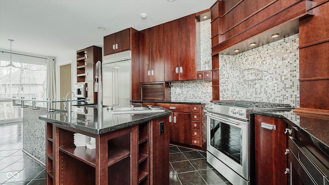 kitchen with high end appliances, hanging light fixtures, decorative backsplash, dark stone countertops, and dark tile patterned floors