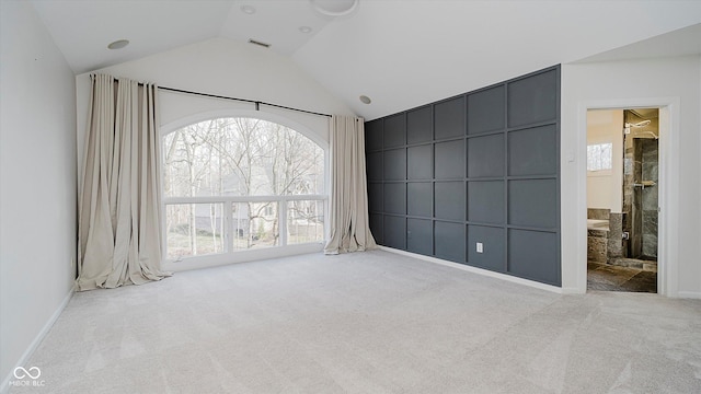 carpeted empty room with vaulted ceiling