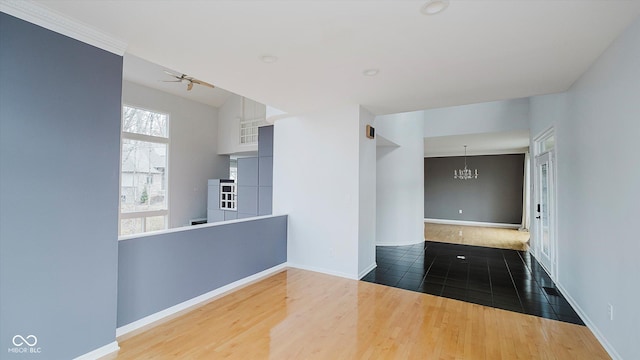 empty room with dark hardwood / wood-style flooring and ceiling fan with notable chandelier