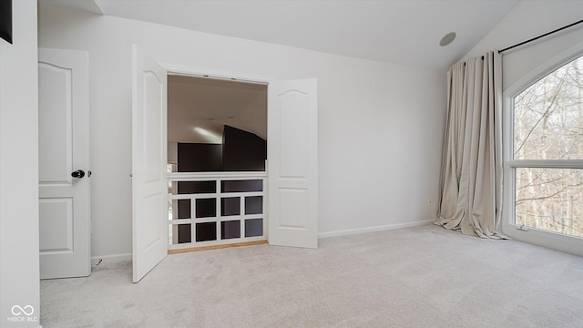 interior space with light colored carpet, a healthy amount of sunlight, and vaulted ceiling