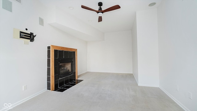 unfurnished living room with carpet flooring, ceiling fan, and a tiled fireplace