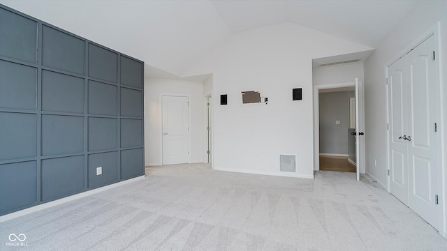 unfurnished room with light colored carpet and vaulted ceiling