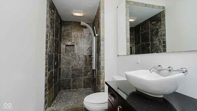 bathroom with vanity, toilet, and a tile shower