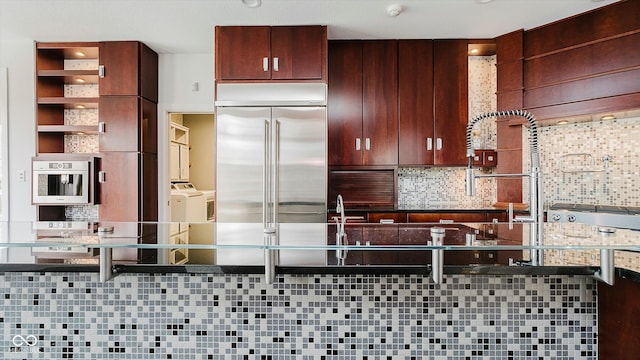 kitchen featuring decorative backsplash, washer and dryer, and built in fridge