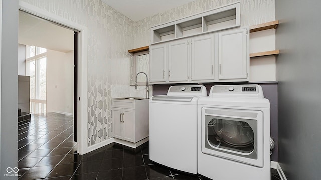 laundry area featuring washer and clothes dryer, dark tile patterned floors, cabinets, and sink