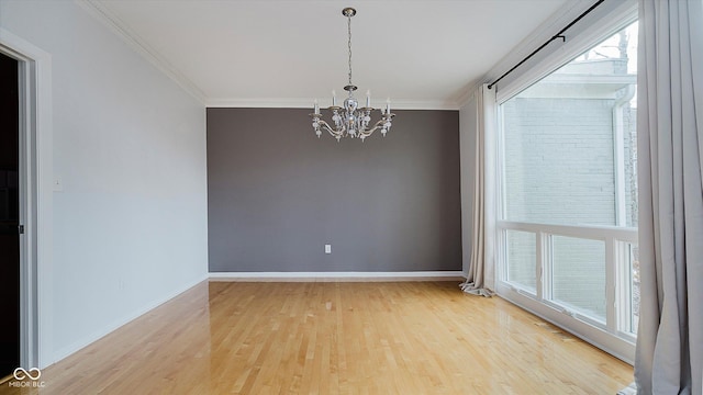 spare room featuring hardwood / wood-style floors, ornamental molding, and a chandelier