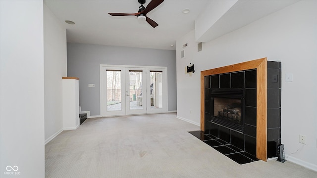 living room featuring a tiled fireplace, ceiling fan, french doors, and carpet floors