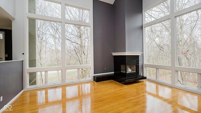 unfurnished living room with a tiled fireplace, a healthy amount of sunlight, and wood-type flooring