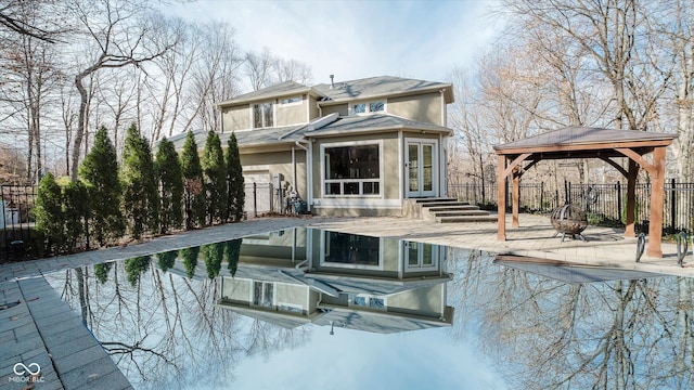 back of property featuring a gazebo, a patio, a fire pit, and a swimming pool