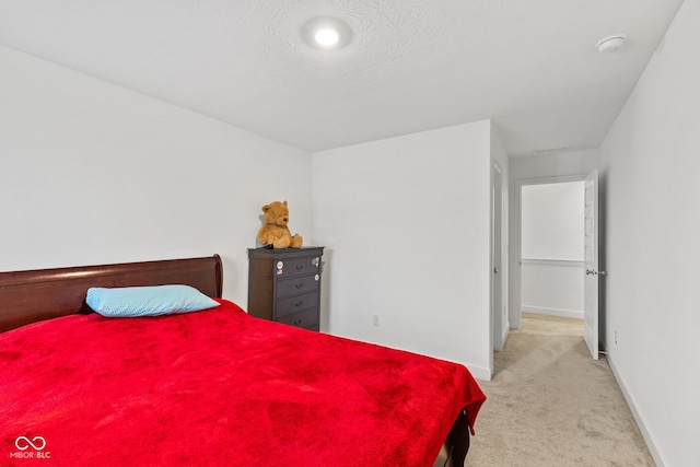 bedroom featuring light colored carpet and a textured ceiling