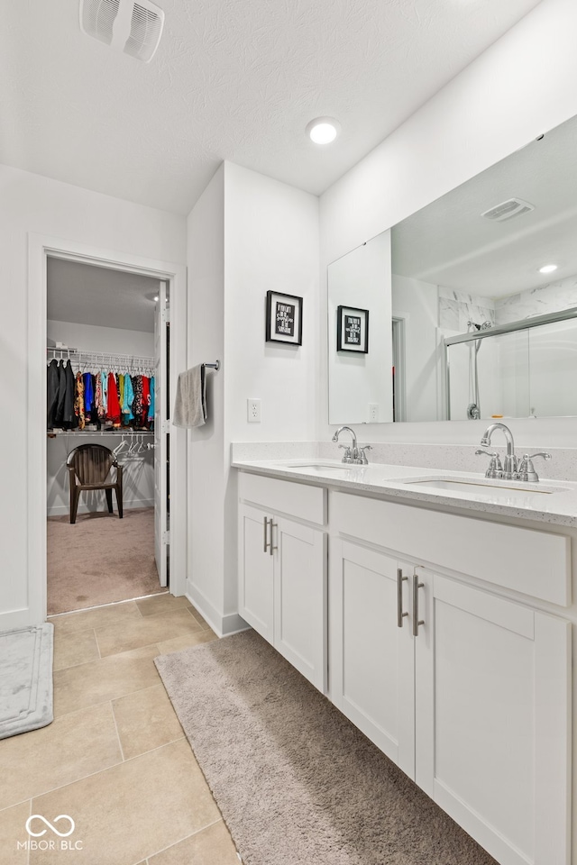 bathroom with a shower with door, vanity, and a textured ceiling