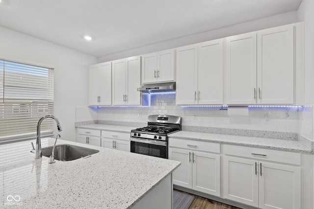 kitchen featuring gas range, white cabinetry, sink, and light stone counters