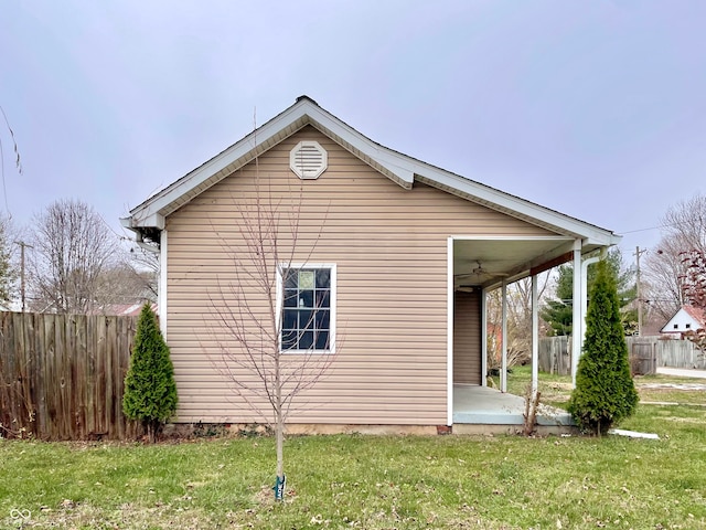 view of side of home with ceiling fan and a yard