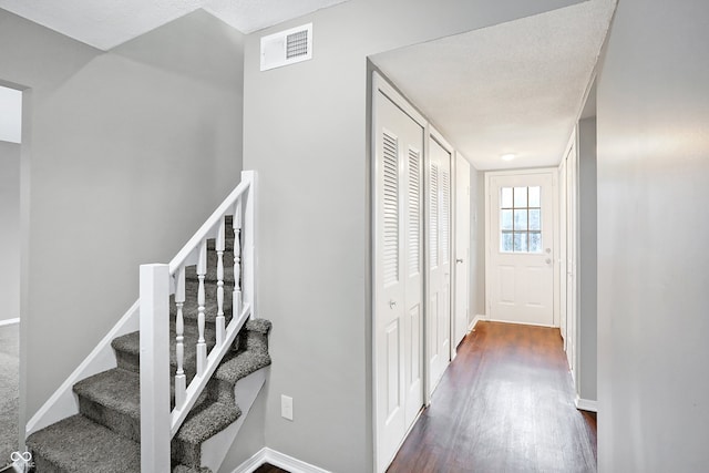 corridor with a textured ceiling and dark wood-type flooring