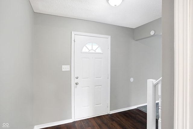 foyer entrance with dark wood-type flooring and a textured ceiling