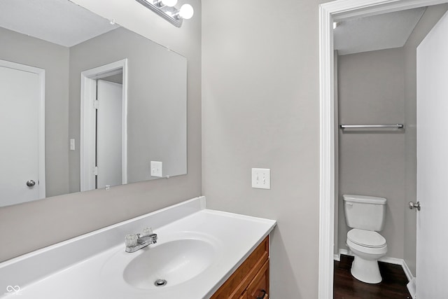 bathroom with hardwood / wood-style flooring, vanity, and toilet