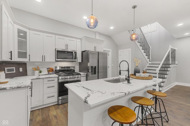 kitchen featuring appliances with stainless steel finishes, sink, pendant lighting, a center island with sink, and white cabinetry