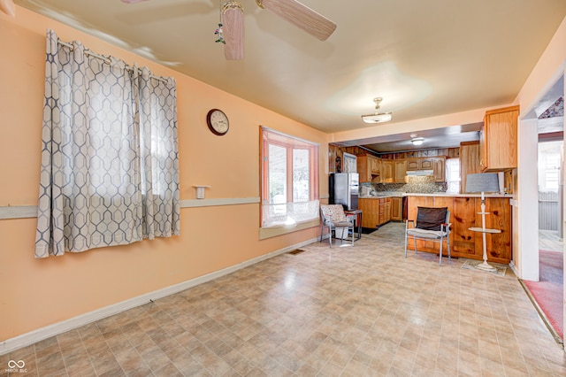 kitchen with kitchen peninsula, stainless steel fridge, a wealth of natural light, and ceiling fan