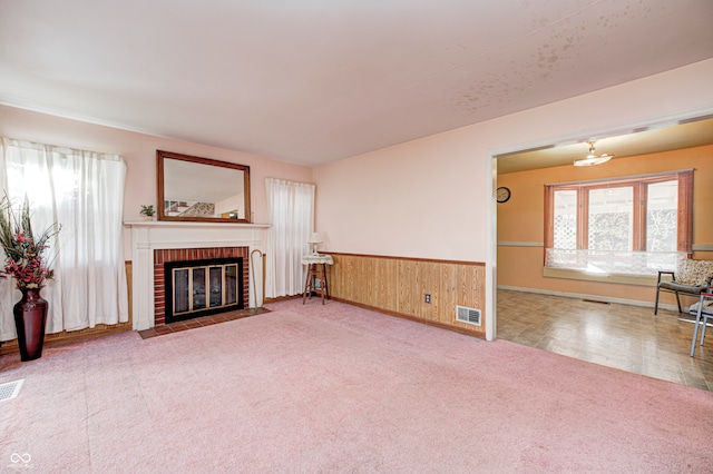 carpeted living room with a fireplace and wooden walls