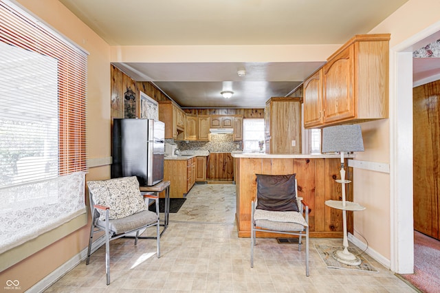 80 S Mickley Ave, Indianapolis, IN 46241 - kitchen with freestanding refrigerator, a peninsula, light countertops, under cabinet range hood, and decorative backsplash