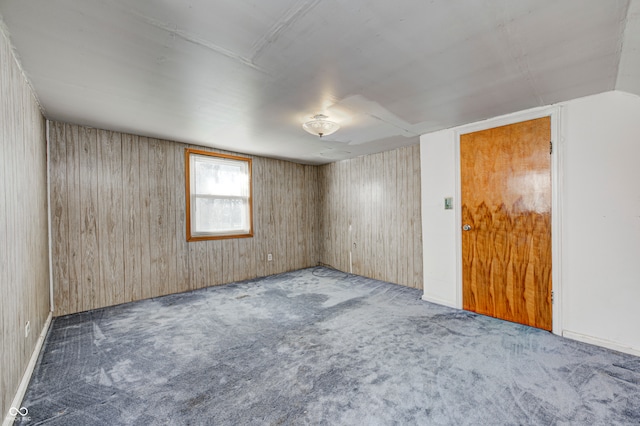 carpeted empty room featuring wood walls