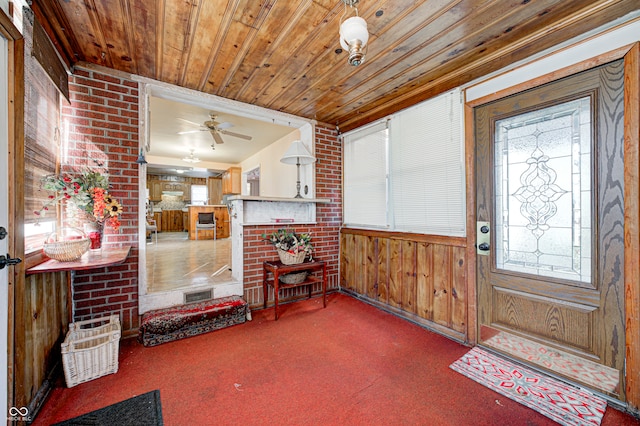 entrance foyer featuring carpet, ceiling fan, a wealth of natural light, and wood walls