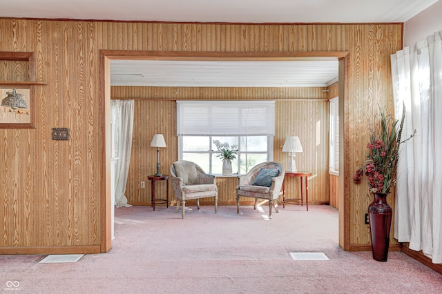 sitting room with carpet and wood walls