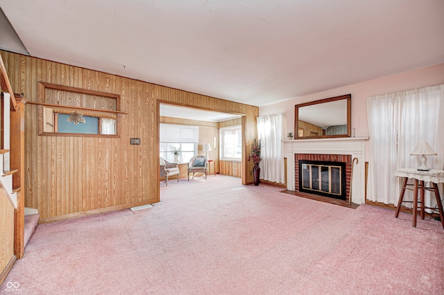 carpeted living room featuring wood walls and a brick fireplace