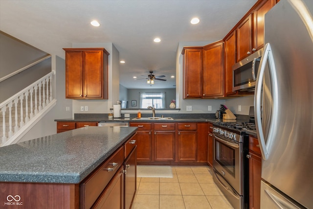 kitchen with sink, ceiling fan, a kitchen island, appliances with stainless steel finishes, and light tile patterned flooring