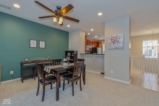 carpeted dining space with ceiling fan with notable chandelier