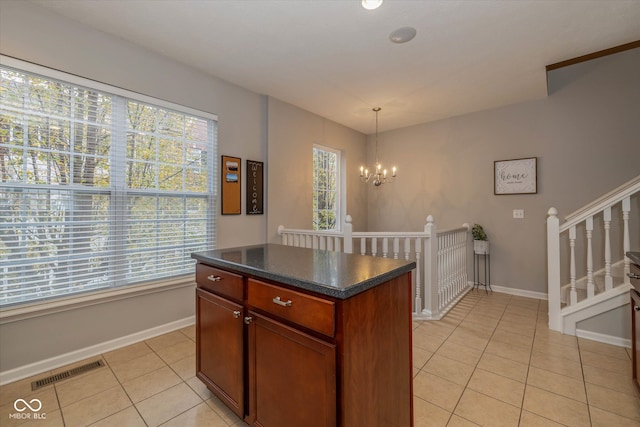 kitchen with light tile patterned flooring, pendant lighting, a kitchen island, and a healthy amount of sunlight