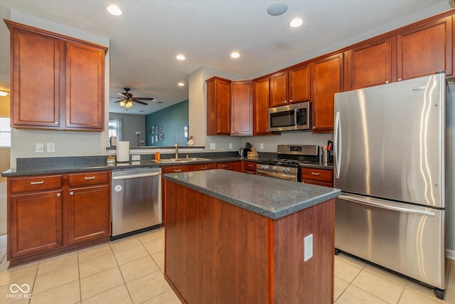 kitchen with kitchen peninsula, stainless steel appliances, ceiling fan, sink, and a center island