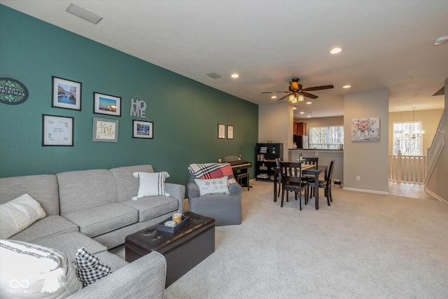 carpeted living room featuring ceiling fan with notable chandelier