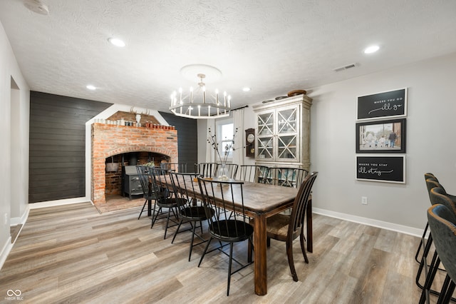 dining room featuring light wood-type flooring, an inviting chandelier, and a textured ceiling