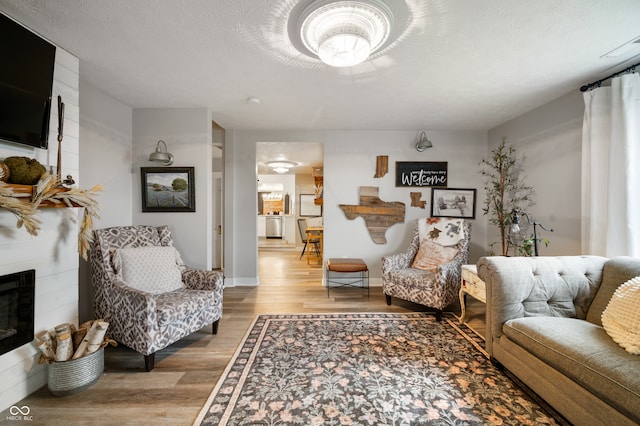 living room with hardwood / wood-style flooring, a textured ceiling, and a fireplace