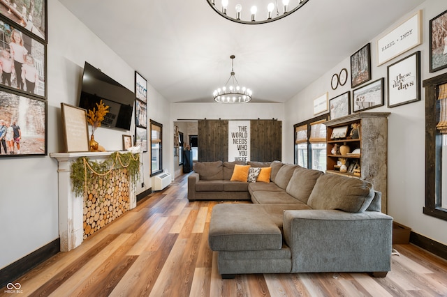 living room with a barn door, a notable chandelier, and hardwood / wood-style floors