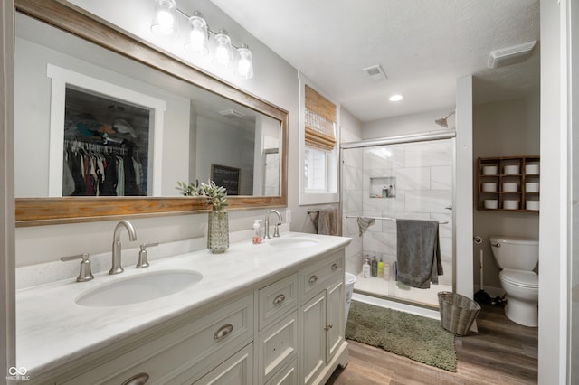 bathroom with hardwood / wood-style flooring, toilet, vanity, and an enclosed shower