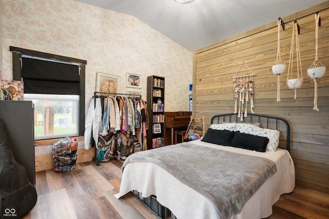 bedroom with vaulted ceiling, hardwood / wood-style floors, and wooden walls